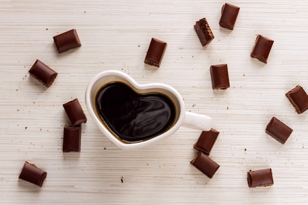 Cup with coffee shaped heart i love you and valentine's chocolate on wood background
