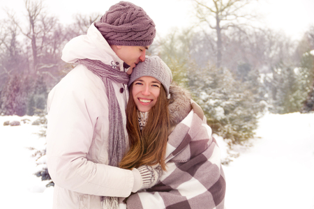 Joyful romantic couple smiling in park in winterの写真素材