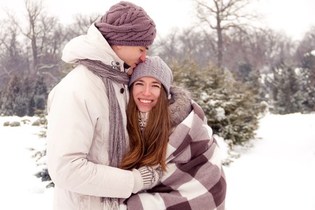 Joyful romantic couple smiling in park in winterの写真素材