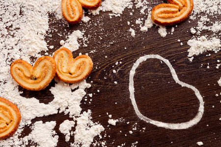 White heart shape from flour with cookies on wooden table. Concept "love cooking"の写真素材