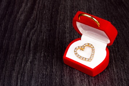 Gold jewelry brooch in shape of heart on wooden background for valentines day as valentines card or backgroundの写真素材