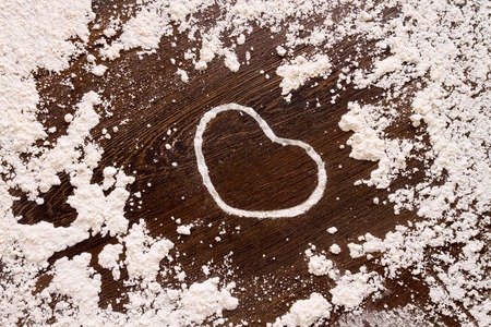 White heart shape from flour on wooden table. Concept "love cooking"の写真素材