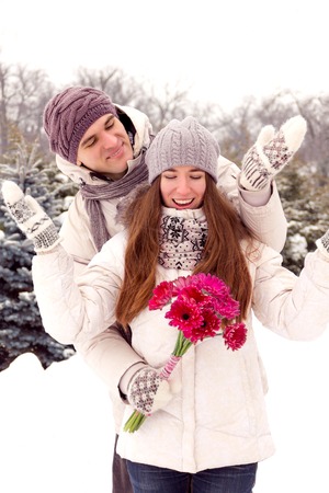 Joyful young romantic couple smiling in park in winter