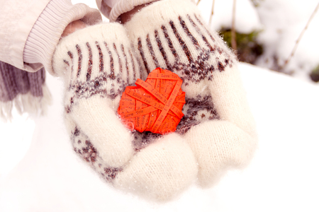 Young male in mittens holding red heart shape from paper for valentine's dayの写真素材