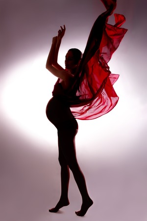 Body contour of pregnant woman in flying tissues in studio with vignettes backgroundの写真素材