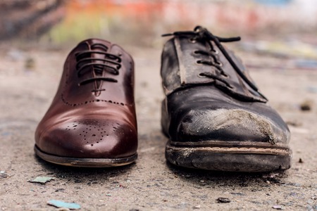 Conceptual shooting of shoes. Old shabby shoes in comparison with new and expensive ones.