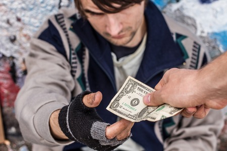 Getting help. Homeless man being handed money by volunteerの写真素材