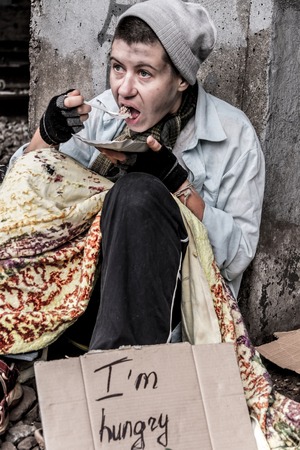 Homeless woman sitting near the rail track having meal