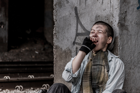 Homeless young woman siiting near the rail track and yawningの写真素材