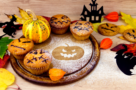 Spooky cupcakes, pumpkin, leaves and silhouette of bat on wooden dishesの写真素材
