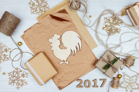 Christmas decoration elements: string, colorful paper, craft envelope, wooden number of the next year, snowflakes, golden beads, figure of wooden rooster and several decorated gifts isolated on white backgroundの写真素材