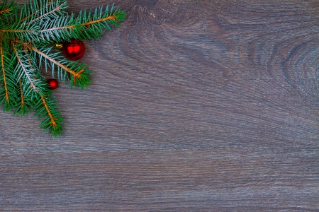 Christmas tree branch decorated with red balls isolated on wooden backgroundの写真素材