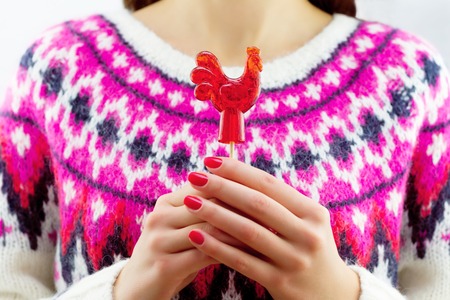 Girl holding red lollipop in form of the roosterの写真素材
