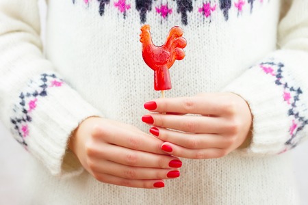Girl holding red lollipop in form of the roosterの写真素材