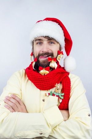 Guy dressed as Santa wearing beard decorated with colorful bows putting out his tongueの写真素材