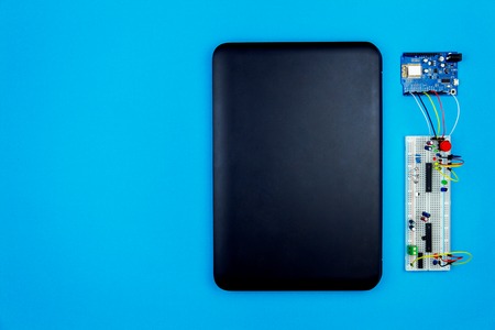 Top view of desktop of  hardware engineer on blue background. Laptop with connectors, microcontroller, microchips and hardware equipmentの写真素材