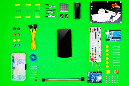Top view of desktop of  hardware engineer on green background. Smartphone with connectors,...