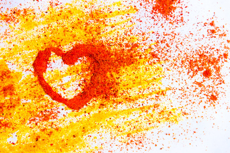 Valentine heart from spices curry and paprika on the white backgroundの写真素材