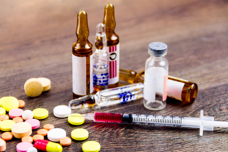 Drugs addiction concept. Drugs injection. Pills, injector, ampules isolated on wooden backgroundの写真素材