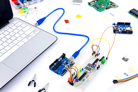 Microcontrollers, chips, resistors, usb cables and notebook on white desktop of hardware engineer....