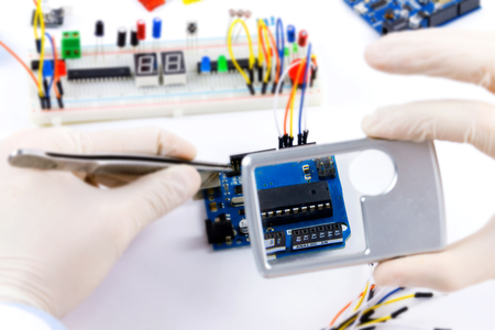 Engineer looking through the loupe on the microchips to fix with tongs
