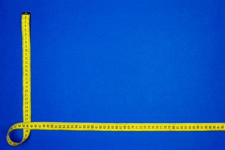 Yellow measuring tape isolated on blue background