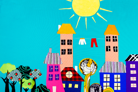 Fabric town. Houses, trees and the sun made of colorful pieces of fabric isolated on blue background.の写真素材