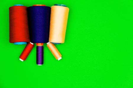 Colorful sewing spools of different size  isolated on green background. 