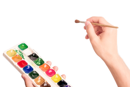 Man's hand holding brush and watercolor paints isolated on white background. Virtual realityの写真素材