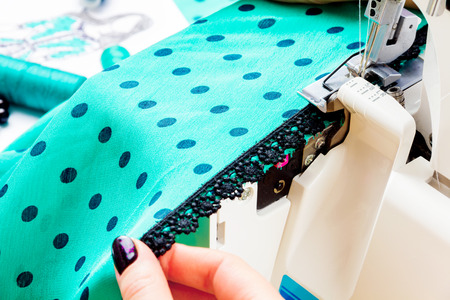 Close up of girls hands sewing dress with the help of sewing machine