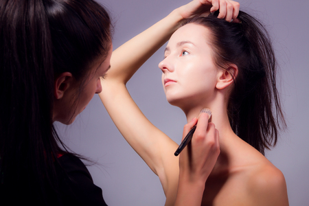 Female / woman / girl preparing for show. Makeup artist with makeup brush doing professional makeup for young woman. Backstageの写真素材