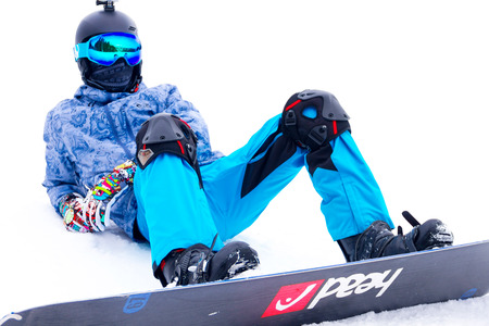 BUKOVEL, UKRAINE - MARCH 12, 2017 Man sitting on the top of the alps mountain  wearing a snowboardのeditorial素材
