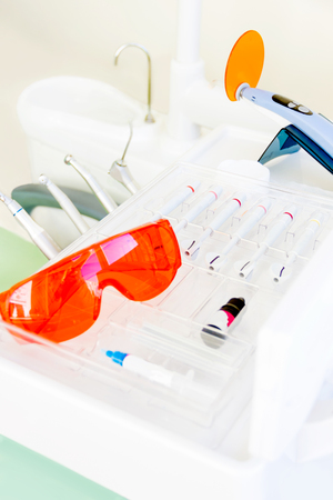 Dentist workplace in clinic. Dental machine equipment tools, red uv glasses and uv instrument for dentist sealants for treatment teethの写真素材