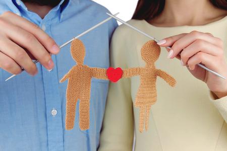 Family concept. Woman and man holding knitted silhouette of young couple in love with red shape of heart by knitted needlesの写真素材