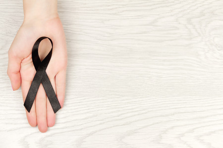 Oncological disease concept. Hand holding black ribbon as a symbol of melanoma. の写真素材