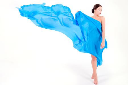 Pure clean beauty pretty girl / woman / female posing with blue and silky fabric as top wearing on white isolated background. Fashion and luxury model conceptの写真素材