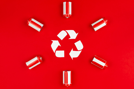 Recycling sign surrounded by red and white batteries isolated on red background. Renewable / green energy concept.の写真素材