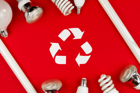 Environmentally friendly world / recycling / green energy concept. White recycling sign surrounded by white light bulbs isolated on red background. Safe environment / ecologyの写真素材