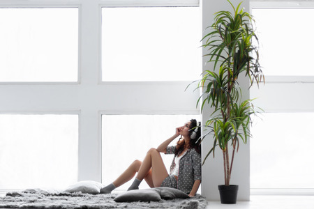 Young girl woman female adult wearing grey pajamas, white top and socks sitting on blanket near the...