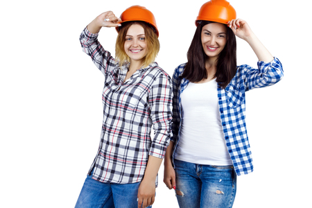 Two happy funny cute architects female woman girl in orange construction protection building helmets on isolated background. Design architecture studio conceptの写真素材