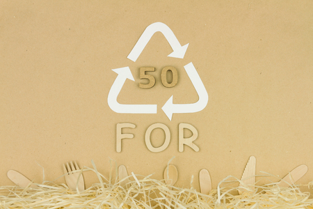 Wooden disposable tableware: forks, spoons and knifes lying on brown background with recycle / reuse symbol with recycling code 50 "FOR". Environment issue / care, recycle / reuse, safe planet conceptの写真素材