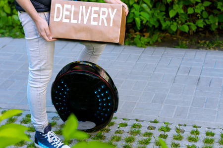 Modern future delivery. Man male guy in delivery uniform and delivery box with electric transport /...
