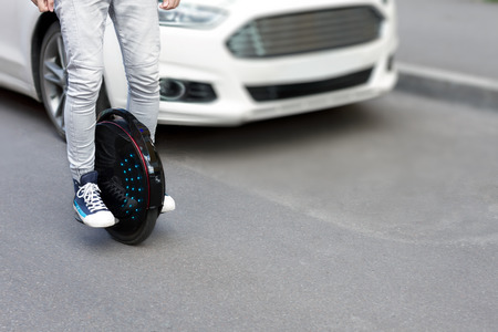 Future is now concept. Ecological transport. Black modern futuristic electric unicycle, unicycle scooter or balancing electric wheel compare with fuel gasoline diesel cars. Eco planet conceptの写真素材