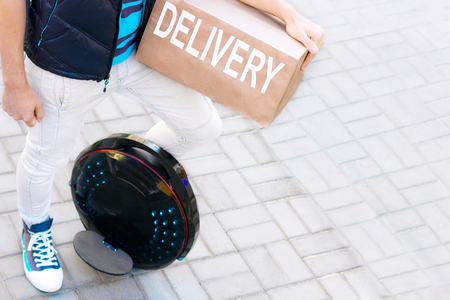 Modern future delivery. Man male guy in delivery uniform and delivery box with electric transport /...