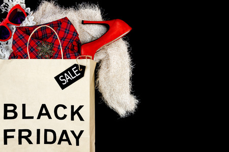 Women female bought a new red high heels and shirt packages in paper shopping bag with text "Black Friday" and sale label. Fashion black friday holiday and sale in shopping mall or cloth store conceptの写真素材