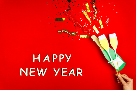 Flat designed champagne boom with confetti and two glasses of champagne as decoration for celebrating Christmas Eve and 2019 Happy New Year party isolated on red background. Merry Christmas concept.の写真素材