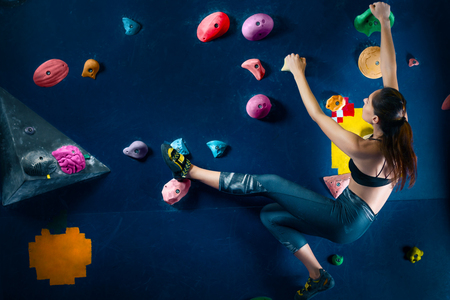 Successful strong confident muscle woman female alpinist climber climbing  to dreams goals, get healthy lifestyle. Training to achieve victory in competition in climbing wall, rock climbing boulderingの写真素材