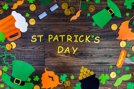 Saint Patrick Day concept. Paper Patrick day leprechaun props: green leprechaun hat orange beard orange mustache and lucky clover trefoil as symbol of Ireland traditional holiday on wooden backgroundの写真素材