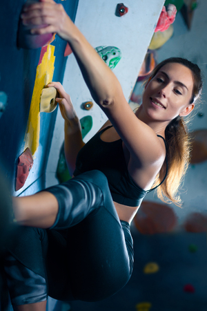 Successful strong confident muscle woman female alpinist climber climbing  to dreams goals, get healthy lifestyle. Training to achieve victory in competition in climbing wall, rock climbing boulderingの写真素材