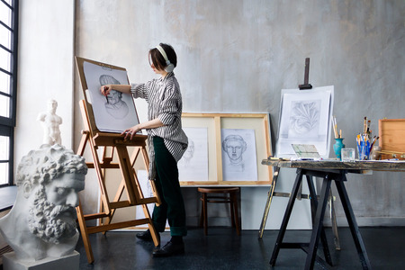 Modern young freelancer artist sculptor woman in headphone creates new art masterpiece drawing...